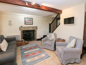 a living room with two chairs and a fireplace at Harry Eyre Cottage in Castleton
