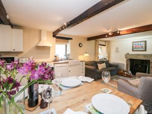 een keuken en een woonkamer met een tafel en stoelen bij Harry Eyre Cottage in Castleton