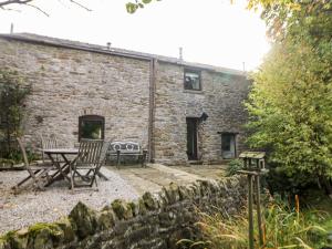 a patio with two chairs and a table in front of a stone building at Harry Eyre Cottage in Castleton