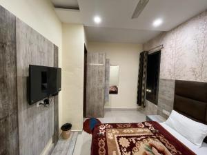 een slaapkamer met een bed en een tv aan de muur bij Shree Krishna Hotels in Amritsar