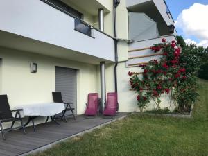 patio ze stołem i krzesłami oraz krzakiem z czerwonymi kwiatami w obiekcie Ferienwohnung Reinstadler Ilse w mieście Jerzens