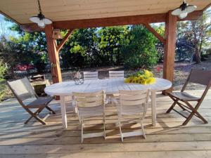 - une table et des chaises blanches sur la terrasse dans l'établissement Chalet calme 3 ch, à Sanguinet