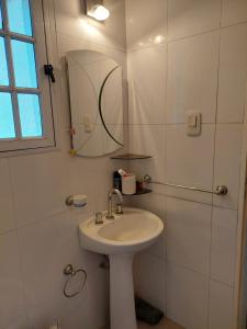 Baño blanco con lavabo y espejo en Sol Mayor en Villa Yacanto