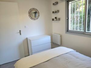 ein weißes Schlafzimmer mit einem Bett und einem Spiegel in der Unterkunft T2 plage de sable à 300m+ parking gratuit in Bandol