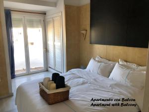 een slaapkamer met een wit bed met een mand erop bij Puerto Marina waterfront apartment in Benalmádena