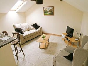 a living room with a couch and a tv at Orchard Cottage in Westward