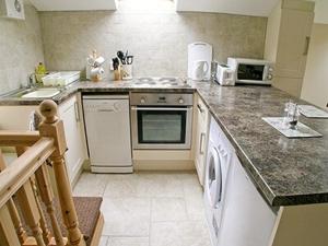 a kitchen with a sink and a stove top oven at Orchard Cottage in Westward