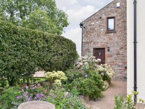 a garden with flowers in front of a brick building at Orchard Cottage in Westward