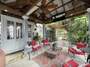 a screened porch with red chairs and a wooden ceiling at Bywater Home, Parking and Pet Friendly Retreat in New Orleans