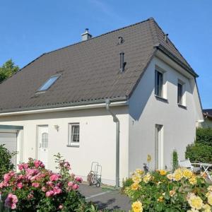 una casa blanca con techo negro y algunas flores en Haus-Am-See-Pratzschwitz, en Pirna