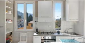 eine Küche mit weißen Schränken, einem Herd und Fenstern in der Unterkunft Nel blu dipinto di blu Apartment in Levanto
