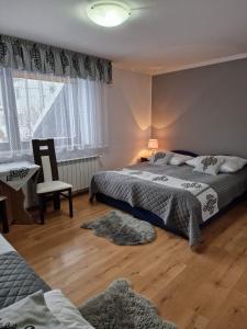 a bedroom with two beds and a chair and a window at Pokoje Gościnne Zych in Szczyrk