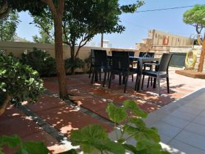 un patio con sillas negras, mesa y árboles en Villiana Holiday Apartments en Stalida