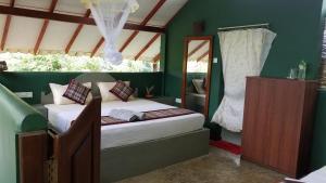 a bedroom with a bed in a room with green walls at Sigiri Holiday Villa in Sigiriya