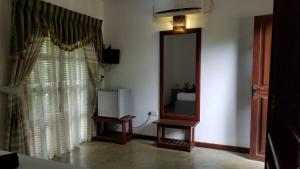 sala de estar con espejo y TV en Sigiri Holiday Villa en Sigiriya