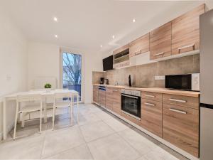 a kitchen with wooden cabinets and a dining table at RAJ Living - City Apartments with 1 or 2 Rooms - 15 Min to Messe DUS and Old Town DUS in Düsseldorf