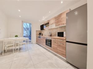 a kitchen with a table and a stainless steel refrigerator at RAJ Living - City Apartments with 1 or 2 Rooms - 15 Min to Messe DUS and Old Town DUS in Düsseldorf