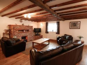 sala de estar con muebles de cuero y chimenea en Tythe Barn, en Kingsley