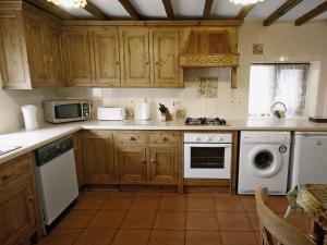 a kitchen with wooden cabinets and a washer and dryer at Tythe Barn in Kingsley
