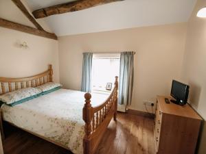 a bedroom with a bed and a tv and a window at Tythe Barn in Kingsley
