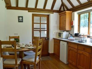a kitchen with a table and chairs and a kitchen with a sink at Ivy Cottage in Sandhurst
