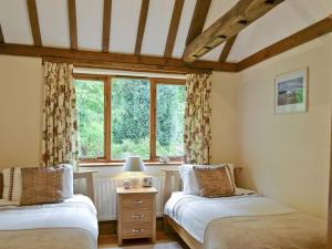 two beds in a room with a window at Ivy Cottage in Sandhurst