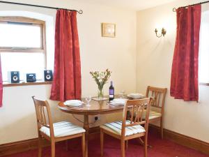 a dining room table with chairs and a bottle of wine at Beech Lodge in Buckland Brewer