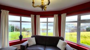 a living room with a couch and large windows at Portfinn Lodge in Leenaun