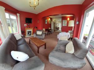 sala de estar con paredes rojas, sofá y sillas en Portfinn Lodge, en Leenaun
