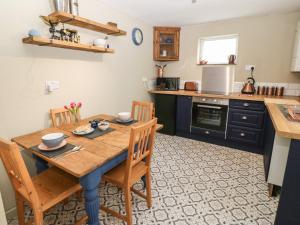 eine Küche mit einem Holztisch und Holzstühlen in der Unterkunft Llety Bach in Caernarfon
