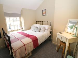 Schlafzimmer mit einem Bett, einem Tisch und einem Spiegel in der Unterkunft Llety Bach in Caernarfon