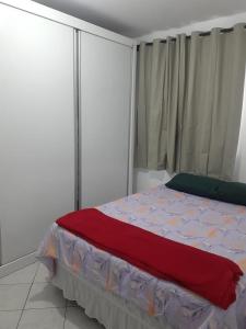 a bedroom with a bed with a red blanket on it at Apartamento bem localizado in São José