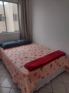 a bed with a red blanket on it with a window at Apartamento bem localizado in São José