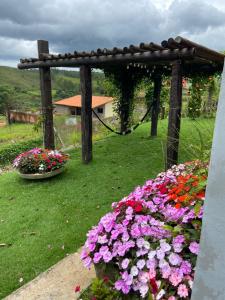 a garden with flowers and a wooden pergola at Pousada Guardiã da Canastra in Vargem Bonita