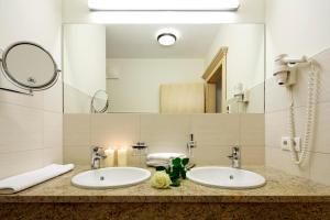 a bathroom with two sinks and a large mirror at Ferienhotel Fuchs in Söll +90 photos