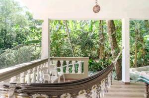 Loft Praia Brava - Suíte com Área Gourmet Privativa في أوباتوبا: أرجوحة على الشرفة الأمامية للمنزل