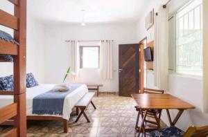 a bedroom with a bed and a desk and a table at Loft Praia Brava - Suíte com Área Gourmet Privativa in Ubatuba