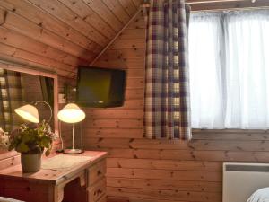 a bedroom with a wooden wall with a television and a table at Wee Ben in Bridge of Tilt
