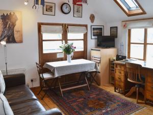 ein Wohnzimmer mit einem Tisch und einer Blumenvase darauf in der Unterkunft Stoker Loft in West Mersea
