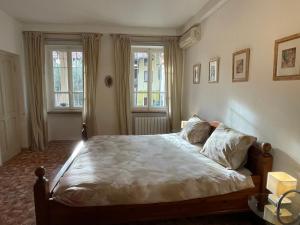 1 dormitorio con 1 cama con sábanas blancas y 2 ventanas en Camelia Casa Vacanze, en Palazzo Canavese