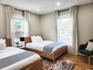 a bedroom with two beds and a chair and windows at Chateau Lodge - Ski Shandaken, Hunter, Catskills, Windham, Belleayre in Shandaken
