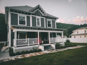 una casa con porche y valla blanca en Chateau Lodge - Ski Shandaken, Hunter, Catskills, Windham, Belleayre, en Shandaken