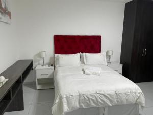 1 dormitorio con 1 cama grande y cabecero rojo en Liso’s Place Guest House en Pretoria