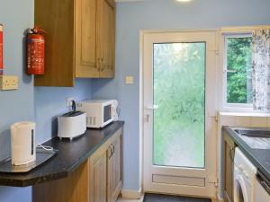 a kitchen with a counter with a microwave and a window at Ryecroft in Bradwell