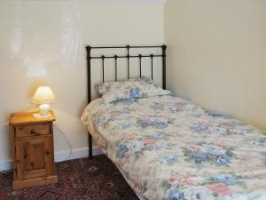 um quarto com uma cama e uma mesa com um candeeiro em Ryecroft em Bradwell