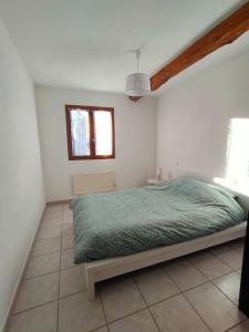 a bedroom with a bed with a green comforter at T3 au pied des Pyrénées in Pointis-de-Rivière