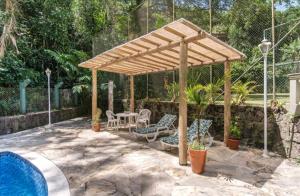 een houten pergola naast een zwembad bij Loft Praia Brava - Suíte com Área Gourmet Privativa in Ubatuba