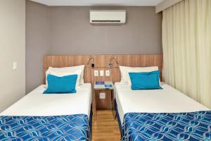 two beds in a small room with blue pillows at Blue Tree Garden Bauru in Bauru