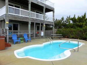 a swimming pool on a patio with blue chairs and a house at KH5007- Fore Sea Suns in Kitty Hawk