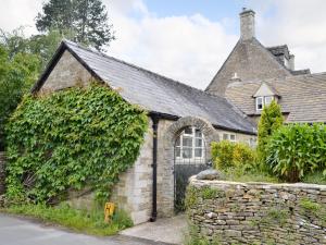 an ivy covered building with a stone wall at Bakery Cottage in Ampney Crucis